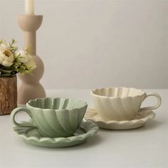 two cups and saucers sitting next to each other on a table