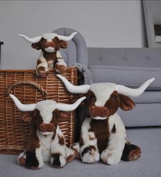 three stuffed cows sitting in front of a wicker basket