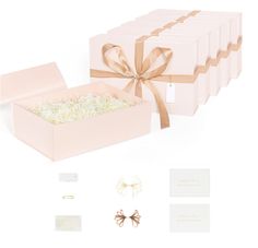 a pink box with gold ribbon and some other items around it, including a bow