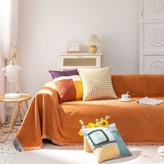 a living room with an orange couch and pillows on top of the couch, next to a coffee table