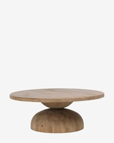 a round wooden table sitting on top of a white wall