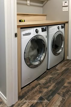 a washer and dryer in a room with wood flooring on the walls