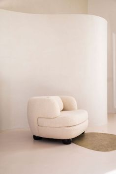 a white chair sitting on top of a floor next to a round rug in a room