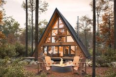 a - frame cabin in the woods with chairs and fire pit on the ground, surrounded by trees