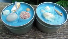 two tins filled with blue liquid and seashells on top of each other