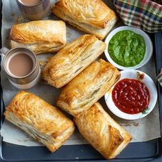 sandwiches and condiments are on a tray with sauces, ketchup