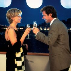 a man and woman standing next to each other holding wine glasses in front of them