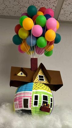 a house with balloons floating from it's roof and in the air, on top of fluffy white foam