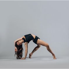 a woman in black leotard doing a handstand with her legs crossed