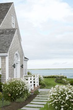 a house with white flowers in front of it and a path leading to the door