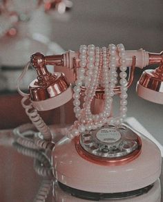 an old fashioned pink phone with pearls on it