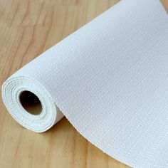 a roll of white fabric sitting on top of a wooden table