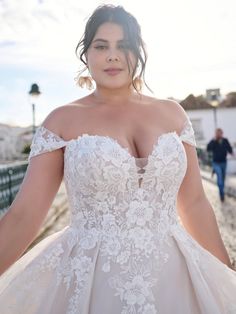 a woman in a wedding dress posing for the camera with her hands on her hips