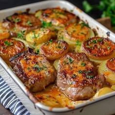 a casserole dish with meat, potatoes and vegetables in it on a table