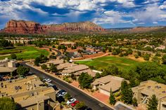 an aerial view of a golf course, mountains and parking lot in the foreground