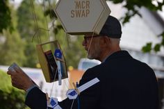 a man in a suit and hat is looking at some items hanging from a sign