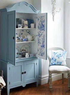 a blue china cabinet sitting next to a white chair