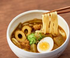 chopsticks sticking out of a bowl of ramen with an egg in it