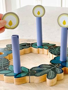 a person is placing candles in the center of a circular wooden table with leaves on it