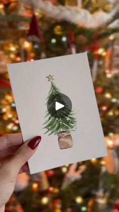 a person holding up a card with a christmas tree on it