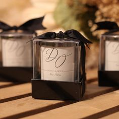 three small square boxes with black ribbon tied around the edges are sitting on a wooden table