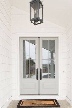 the front door to a house with two double doors and a light fixture above it