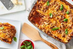 two plates with lasagna casserole on them next to a wooden spatula