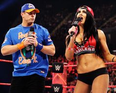 a woman in a wrestling outfit standing next to a man holding a microphone