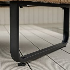 a wooden bench sitting on top of a tiled floor next to a metal frame wall