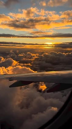 an airplane wing with the sun setting over clouds