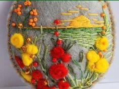 an embroidered object with flowers and grass on it