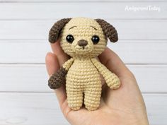 a hand holding a small crocheted dog