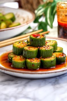 cucumber slices on a plate with sauce and chopsticks in the background