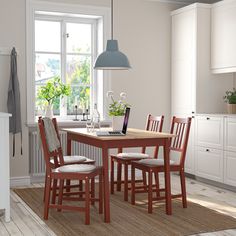 a kitchen table with four chairs and a laptop on it