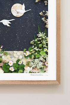 an art work with flowers and birds flying over the moon, in a wooden frame