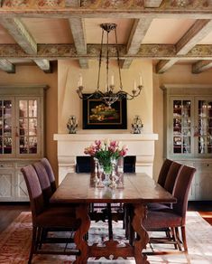 a dining room table with chairs and a chandelier hanging from the ceiling above it