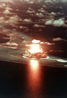 an oil rig spewing flames into the air over a small island in the ocean