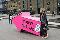 a woman standing next to a pink sign that says you've arrived on it