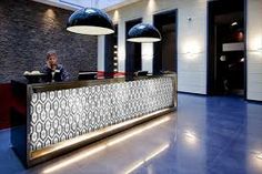 a woman sitting at the front desk of a hotel lobby with blue tile flooring