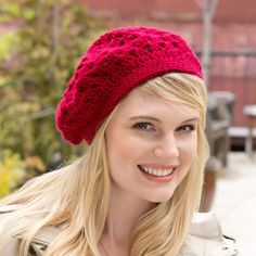 a woman with blonde hair wearing a red knitted hat and smiling at the camera