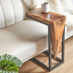 a wooden table sitting on top of a white couch next to a potted plant