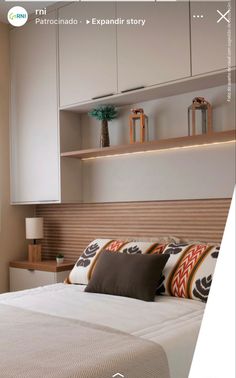 a bed sitting under a window next to a wall mounted book shelf in a bedroom