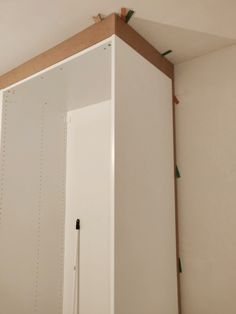 an unfinished room with white cabinets and pegs on the wall, including one door