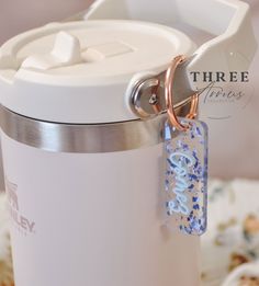 a close up of a cup with a keychain attached to the handle and a tag on it