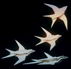 three origami birds are flying in the air together, one is white and the other is black