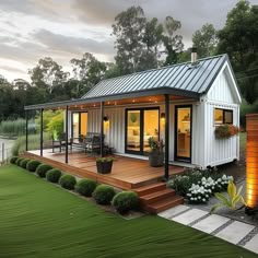 a small white house sitting on top of a lush green field next to a lake