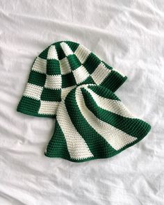 two green and white crocheted hats sitting on top of a bed