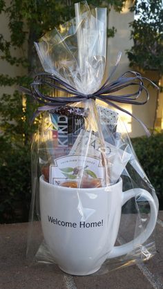 a welcome home coffee mug filled with tea and cookies wrapped in cellophane to give as a gift