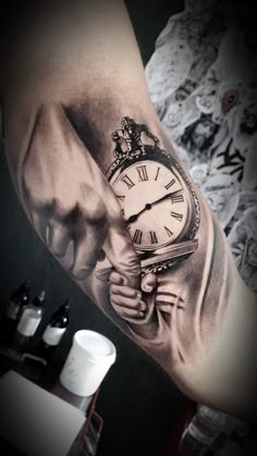 a man's arm with a clock tattoo on it and his hand holding the clock