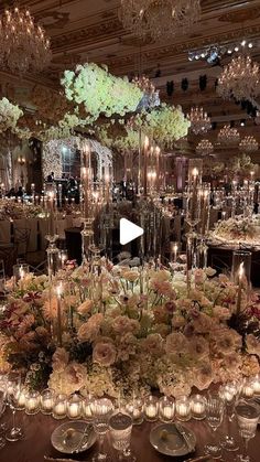 a table with candles and flowers on it in a room filled with chandeliers